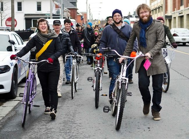 B!ke’s executive director Tegan Moss, left, leads a bike parade of volunteers and community members across Charlotte St. on Sunday. The parade was a way to move the shop’s 60 bikes and parts to its new location. B!ke is leaving its Rubidge St. space for a bigger spot on George St. Photo courtesy of Jessica Nyznik/Peterborough Examiner